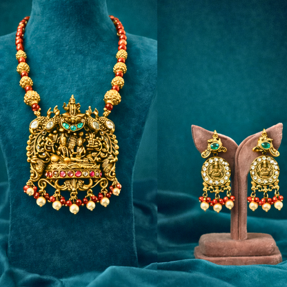 Gold necklace with red beads and matching earrings on a blue background